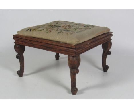 An unusual early Victorian carved yew-wood Dressing Stool, the loose drop in seat with floral needlework, on four carved cabr