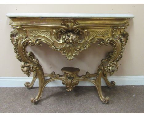 An very fine early 19th Century carved giltwood Console or Side Table, the serpentine shaped moulded marble top, over a profu