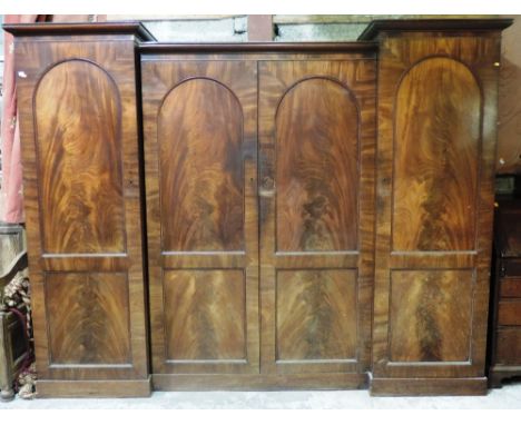 A fine early 19th Century Irish figured mahogany inverted breakfront Wardrobe, with moulded cornice over four arched panel do