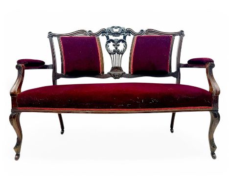 Late Victorian stained beech framed sofa, the backrests, seat and padded arms upholstered in deep red fabric, carved crest ra