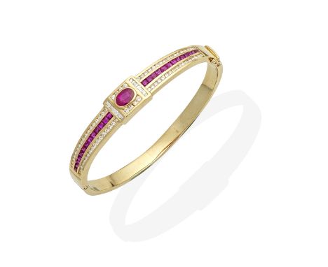 RUBY AND DIAMOND BANGLEThe hinged frontispiece set with an oval-cut ruby, between calibré-cut rubies, and baguette and brilli