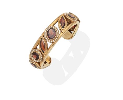 ZILLA: GARNET AND DIAMOND BANGLEThe openwork torque bangle set with circular, oval and marquise-cut garnets and brilliant-cut