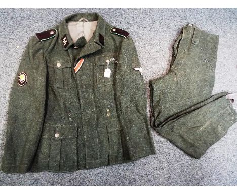 A World War Two (WWII) German Waffen SS uniform with patch badges to collar and sleeves, with trousers marked 74/110 - Est £8