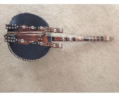 An African tribal 9-stringed Kora harp guitar with round back depicting a map of Africa, made of hide with shell decoration a