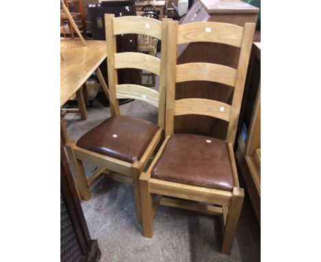 A set of four modern light oak ladder back dining chairs with brown leatherette seats