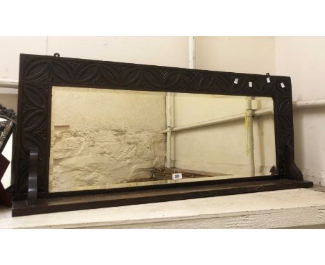 An early 20th Century stained and carved oak framed wall mirror with bevelled oblong plate and bracketed shelf
