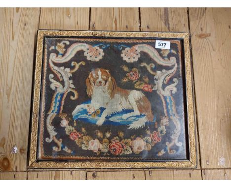 An antique tapestry panel depicting a spaniel recumbent upon a cushion with foliate Rococo scroll border, set in later frame