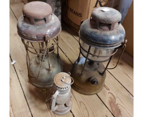 A box containing two vintage Tilly lamps and a small hurricane lamp