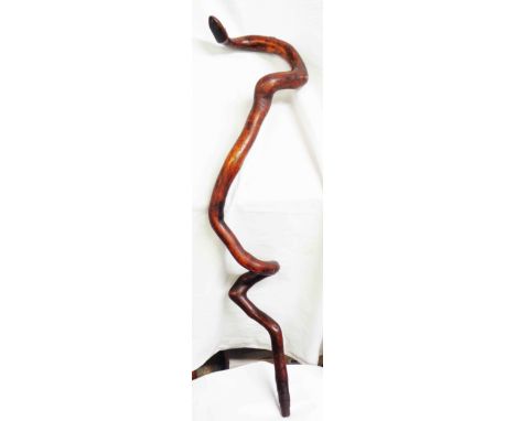 An antique folk art walking stick made from a gnarly twisty branch in the form of snake with simple nail head eyes and iron f