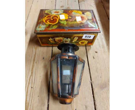 A vintage biscuit tin containing an old candle lamp
