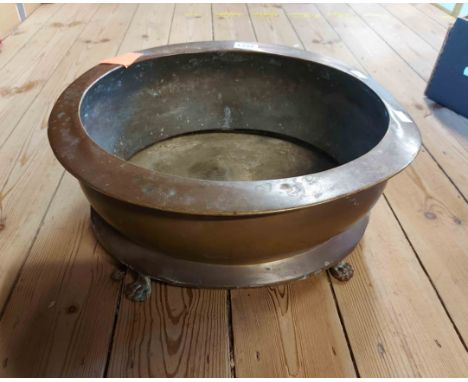 A large old brass oval planter with cast lion paw feet