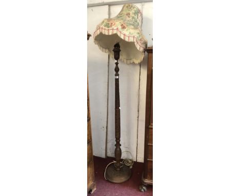An Indian hardwood standard lamp with carved pillar and circular base, with shade