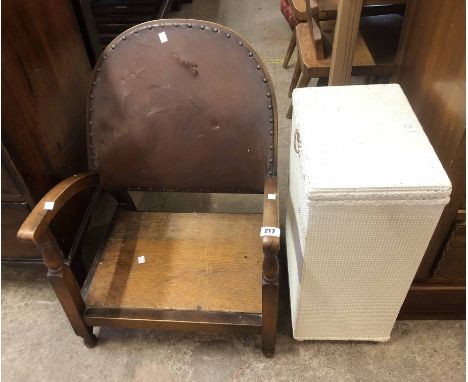 An early 20th Century mixed wood framed low elbow chair with studded leather back panel - sold with a loom style laundry bask