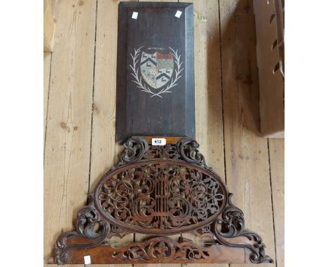An antique painted wooden armorial panel with fielded edges - sold with a fretwork music stand (a/f)