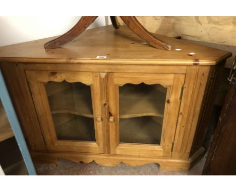 A 1.07m modern waxed pine corner cabinet enclosed by a pair of glazed panel doors, set on bracket base