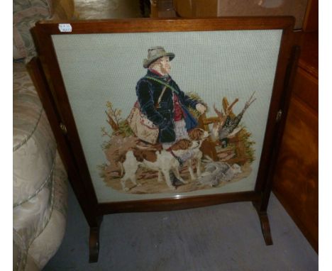 A MAHOGANY GRATE SCREEN WITH GLAZED AND PICTORIAL NEEDLEWORK TAPESTRY PANEL DEPICTING A HUNTSMAN AND DOGS, ON CHEVAL FEET