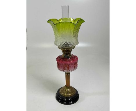 An oil lamp with cranberry reservoir and green shade, height 56cm.Condition Report: There is a crack across the base of the s