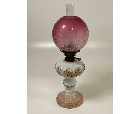 An oil lamp with a cranberry glass shade, height 56cm