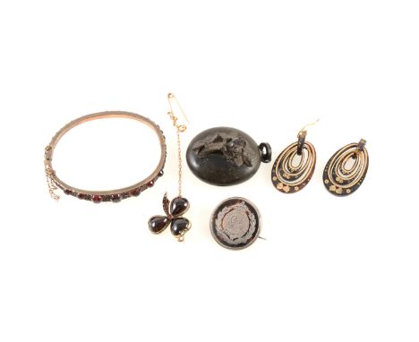 A yellow metal half hinged bangle with graduated garnets in closed back settings, bangle graduating from 8.5mm wide at front 