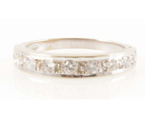 A diamond half eternity ring, nine brilliant cut diamonds graduating in size, set in a white metal line edge mount with beads