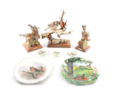 A Capodimonte resin bird model, sparrow on a snow covered branch, wooden base, 28cm; three other Capodimonte bird models, oth