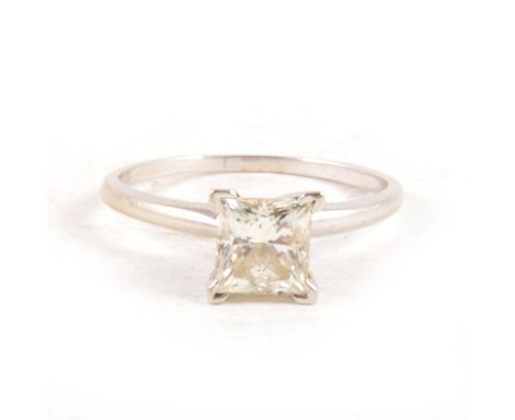 A diamond solitaire ring, the rectangular princess cut stone four claw set in an all white metal mount, plain polished D shap