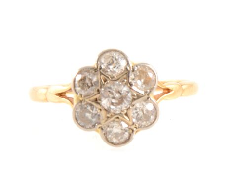 A circular floral design diamond cluster ring, the old brilliant cut diamonds pip claw and collet set in a yellow and white m