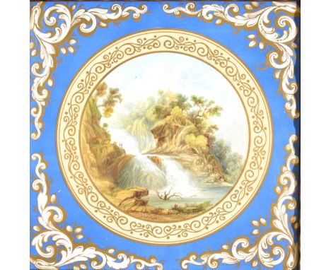 A handpainted porcelain plaque/ tile, central roundel with figures aside a cascading waterfall, in gilt scrolled borders and 