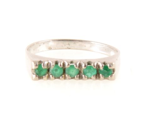 An emerald half hoop ring, five 8 cut emeralds claw set horizontally in an all white metal mount, shank marked 18ct, gross we