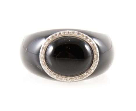 A black domed ring with oval circle of thirty-six small diamonds, yellow metal disc inside ring marked K18 750, ring size R.