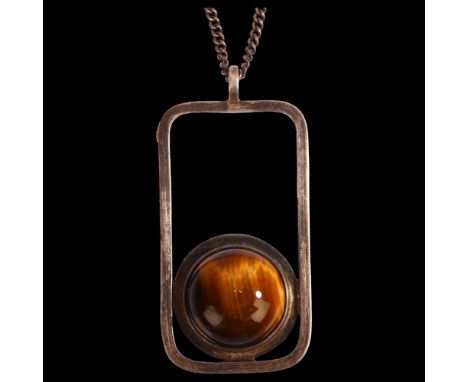 A Scottish modernist silver and cabochon tigers eye set abstract pendant on silver chain, marked KND Edinburgh 1980, length e