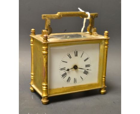 A French lacquered brass carriage clock, white rectangular enamel dial, Roman numerals, swing carry handle, column supports, 