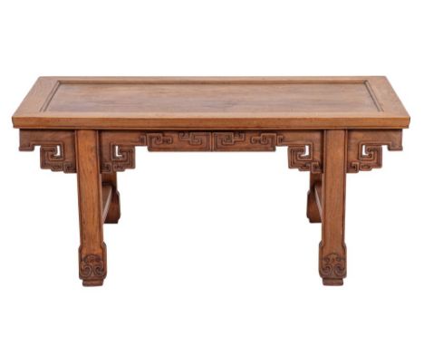 A Chinese hardwood low table, early 20th century; the cleated rectangular top with recessed central panel; above relief carve