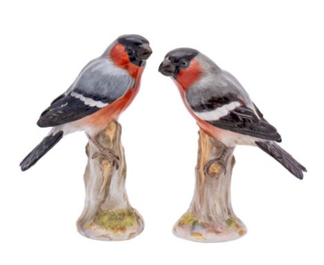 A pair of Meissen figures of bullfinches naturalistically modelled perched on tree stumps, crossed swords and incised marks, 