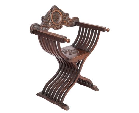 An Italian carved walnut Savanarola elbow chair, late 19th century; the backrest with a central roundel with floral pendant c