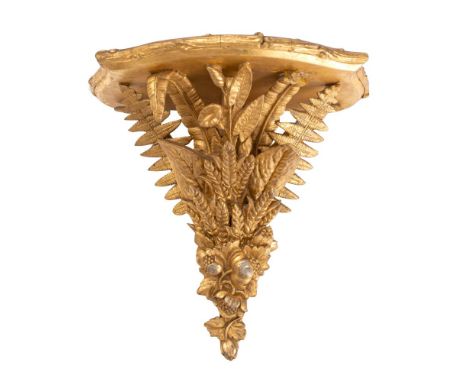 A 19th century giltwood wall bracket the shelf of bowed outline with reeded border, supported on a spray of fern leaves, palm