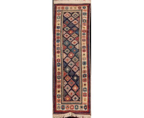 A Shirvan runner:, the indigo field with a design of serrated lozenges enclosed by a main ivory calyx medallion border, 265cm