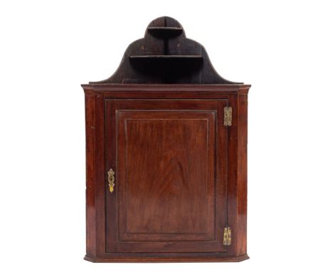 A George III mahogany hanging corner cabinet., late 18th century; the galleried two tier top with serpentine sides; above a c