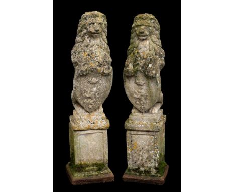 A pair of stone composition garden models of heraldic lions, 20th century; each portrayed as sejant erect, with forepaws supp