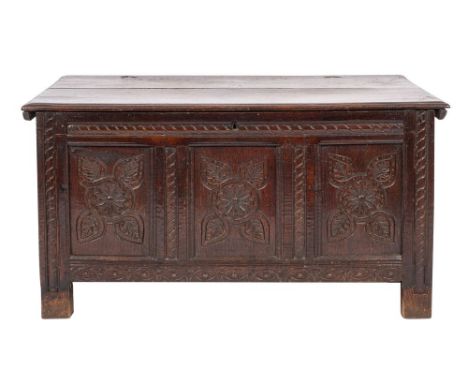 A Charles II oak coffer, circa 1680; the hinged cover with moulded edging; the three panel front with stylised floral and fol