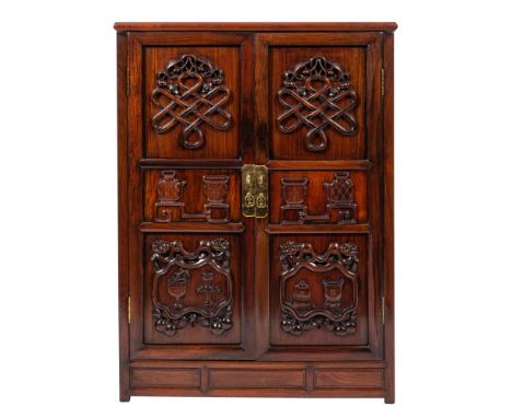 A Chinese carved and stained hardwood side cupboard, late 19th / early 20th century; the top with recessed panel and moulded 