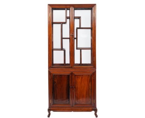 A Chinese stained hardwood display cabinet, late 19th / early 20th century; the upper section glazed to front, back and sides