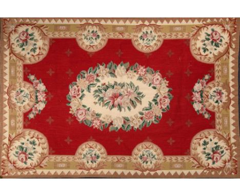 An Aubusson style flat weave panel the wine red field with central floral medallion, enclosed by smaller medallions to the tr