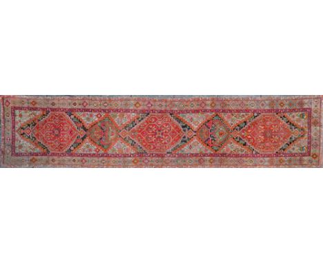A Persian runner, early 20th century,: with three brick red lozenge shaped reserves interspersed with smaller reserves, all c
