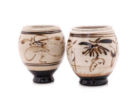 TWO CIZHOU WHITE-GLAZED AND PAINTED JARS
Ming dynasty, oviform standing on narrow black glazed foot, decorated in white slip 