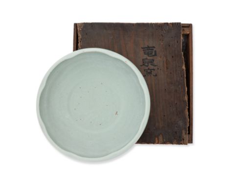 A CELADON GLAZED BOWL WITH FOLIATE RIM
Circular shallow bowl covered in pale blue-green celadon glaze, the recessed circular 
