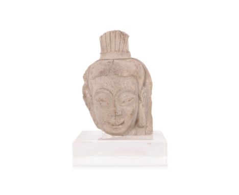 A STONE HEAD OF A BODHISATTVA Chinese, modelled with high arched eyebrows, elongated earlobes and ushnisha in a streaked bun,