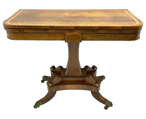 Regency rosewood and brass inlaid card table, the rectangular fold-over and swivelling top with rounded corners with a satinw