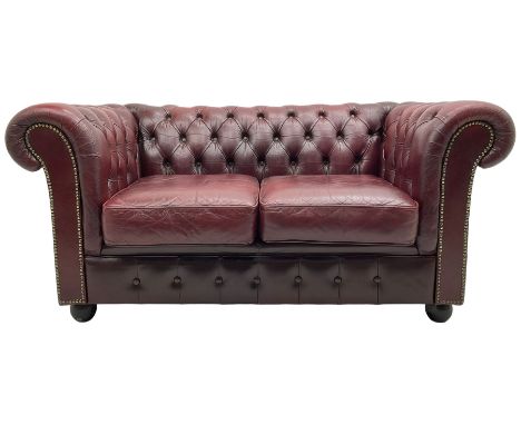 Two seat Chesterfield sofa, upholstered in buttoned oxblood leather with loose seat cushions, on bun feetDimensions: Height:&