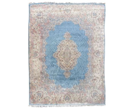 Large Persian design carpet, plain light blue field with floral design central medallion, scrolling foliate spandrels and bor